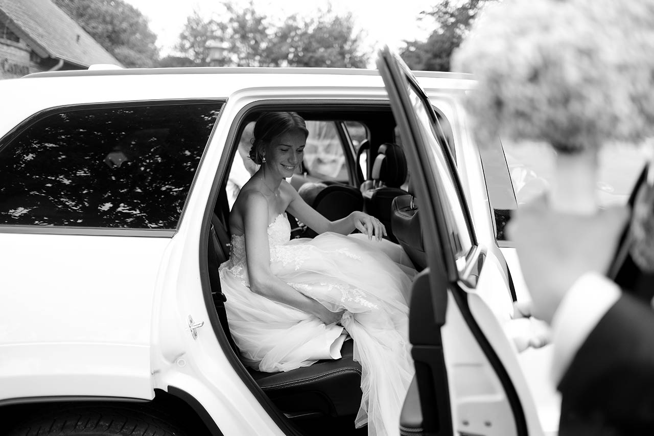 Hochzeitspaar jubelt im Cabriolet